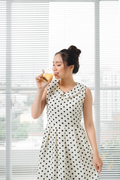 Jeune femme asiatique attirante buvant du thé chaud à la maison