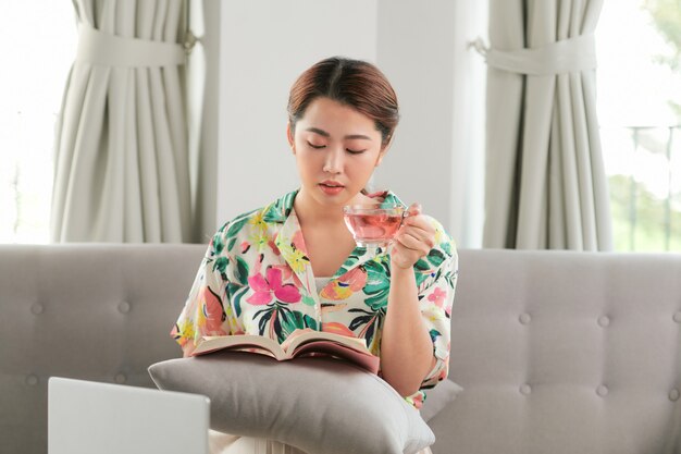 Jeune femme asiatique attirante qui lit un livre