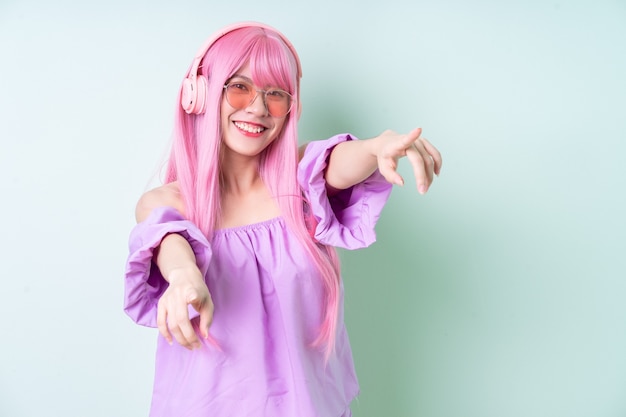 Jeune femme asiatique aux cheveux roses posant sur fond vert