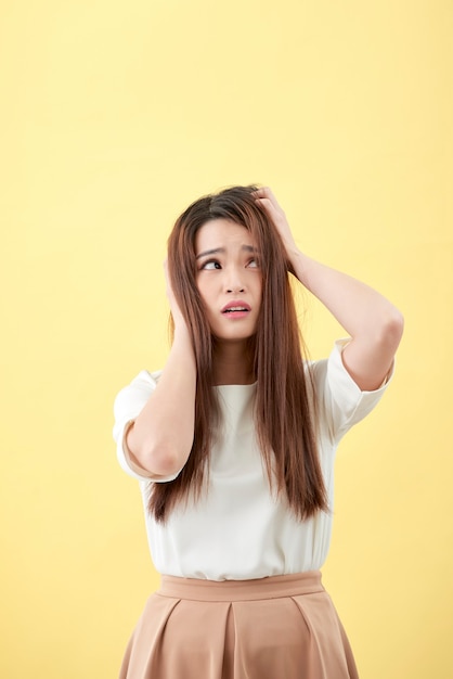 Jeune femme asiatique ayant un stress isolé sur fond jaune.