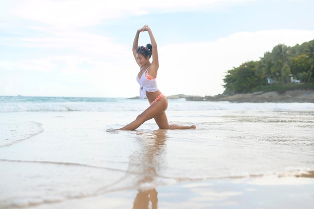 Jeune femme asiatique en bikini faisant du yoga sur la plage concept de santé et de méditation