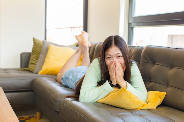 Jeune femme asiatique à la bouche heureuse, joyeuse, chanceuse et surprise couvrant les deux mains