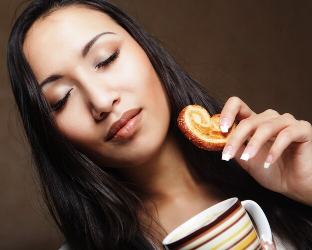 Jeune femme asiatique avec café et biscuits.