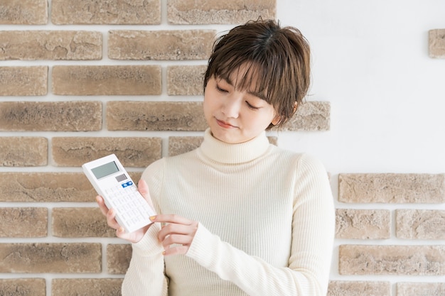 Jeune femme asiatique avec une calculatrice et un regard sévère