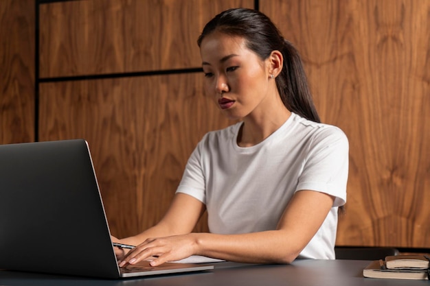 Jeune femme asiatique concentrée tapant sur un ordinateur portable
