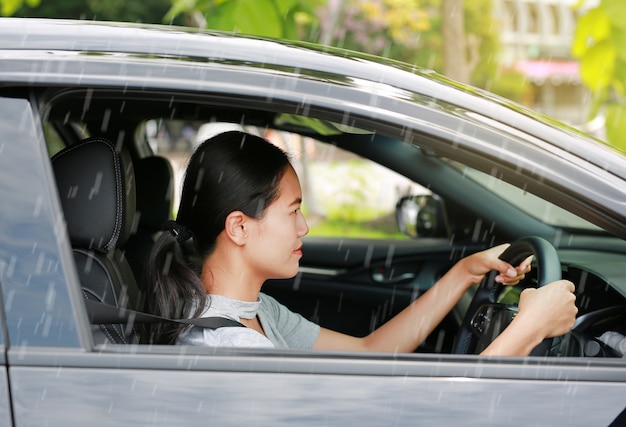 Jeune Femme Asiatique Conduisant Une Voiture Alors Qu'il Pleuvait.