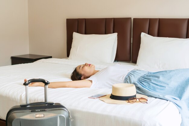 Photo jeune femme asiatique couchée dans le lit d'une chambre d'hôtel. concept de voyage