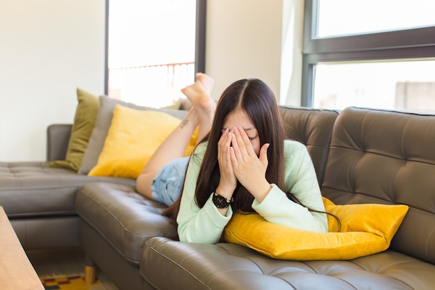 Jeune femme asiatique couvrant les yeux avec les mains avec un regard triste et frustré de désespoir, pleurer, vue de côté