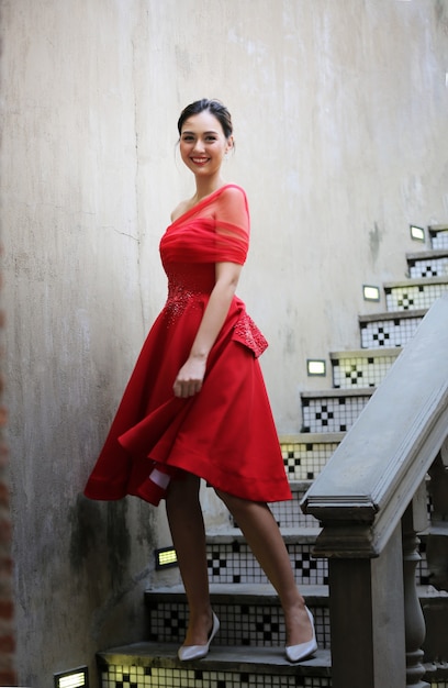 Jeune femme asiatique dans une belle robe rouge regardant la caméra avec le sourire. Mannequin, mariée ou concept de pré-mariage.