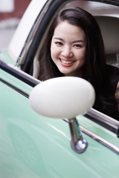 Jeune femme asiatique dans une voiture de collection