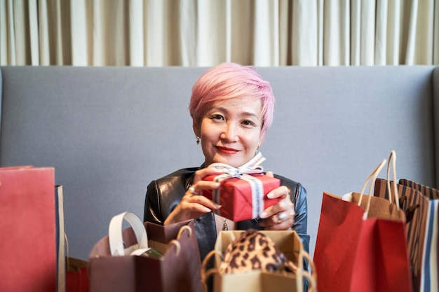 Photo une jeune femme asiatique déballant un cadeau de noël.