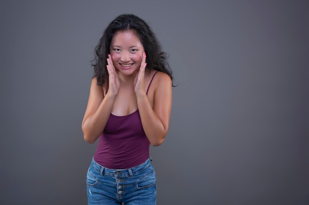 Jeune femme asiatique en débardeur avec une drôle d'expression isolée de l'arrière-plan