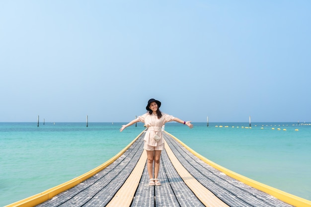 Jeune femme asiatique debout sur la passerelle du ponton en mer tropicale