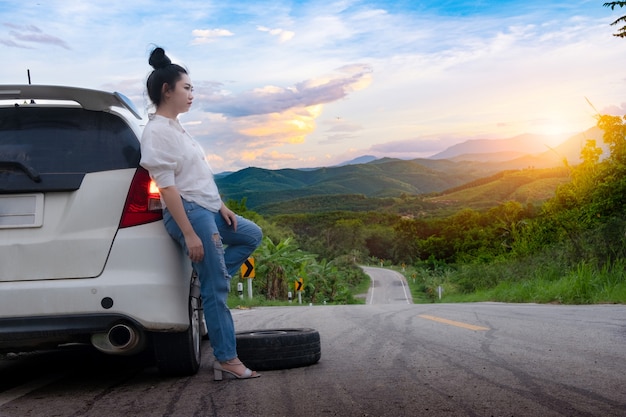 Jeune femme asiatique debout près de la voiture pour avoir appelé à l'aide sur la voie publique