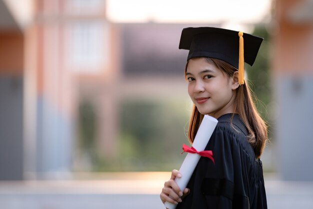 Jeune femme asiatique diplômés universitaires en robe de graduation et mortier détiennent un certificat d'études