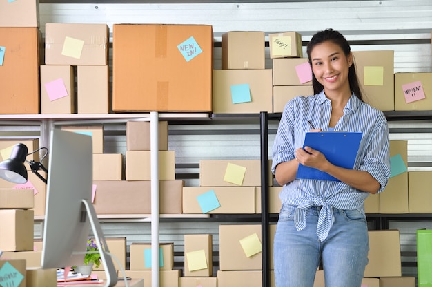 Jeune femme asiatique entrepreneur Chef d'entreprise travaillant à la maison pour faire des achats en ligne et préparer le package de produit