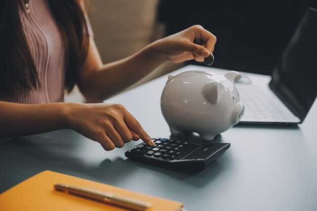 Une jeune femme asiatique épargne pour la retraite épargne de l'argent par le biais d'une tirelire et prend des notes sur le concept d'épargne de notebook