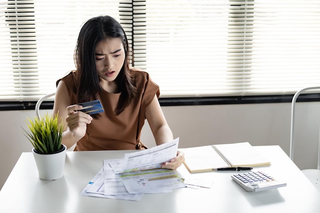 Une jeune femme asiatique est choquée par le stress et réfléchit trop à la dette de nombreuses cartes de crédit et factures. Concept de problème financier. Les femmes ont trouvé un moyen de sortir de la dette à portée de main.