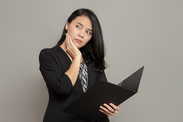 Jeune femme asiatique avec une expression faciale anxieuse tout en tenant un dossier