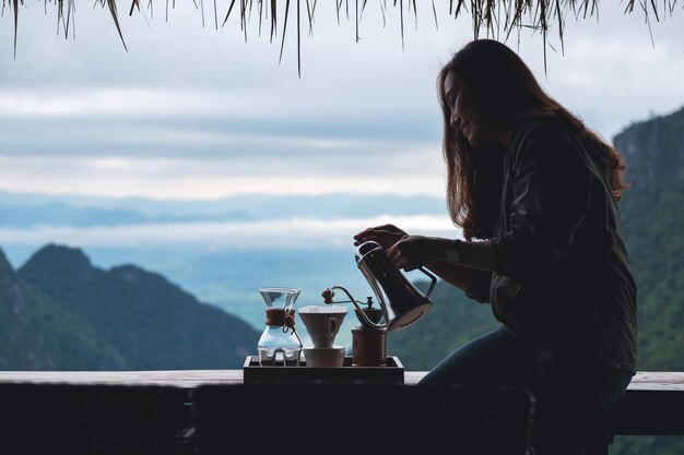 Une jeune femme asiatique faisant du café goutte à goutte avec un beau fond de montagne et de nature