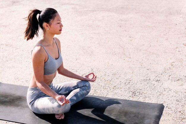 Photo une jeune femme asiatique faisant de la méditation sur un tapis de yoga