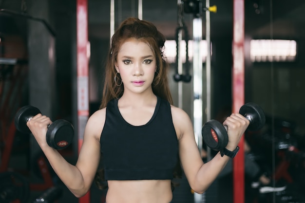 jeune femme asiatique fitness exercice avec machine Cable Crossover et soulever des haltères et des haltères i