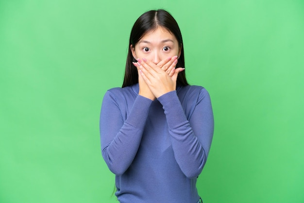 Jeune femme asiatique sur fond isolé chroma key couvrant la bouche avec les mains