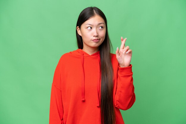 Jeune femme asiatique sur fond isolé pointant vers l'avant et souriant