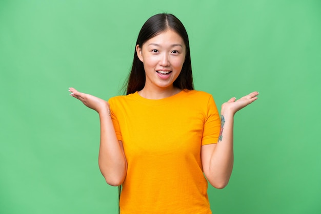 Jeune femme asiatique sur fond isolé souriant et montrant le signe de la victoire