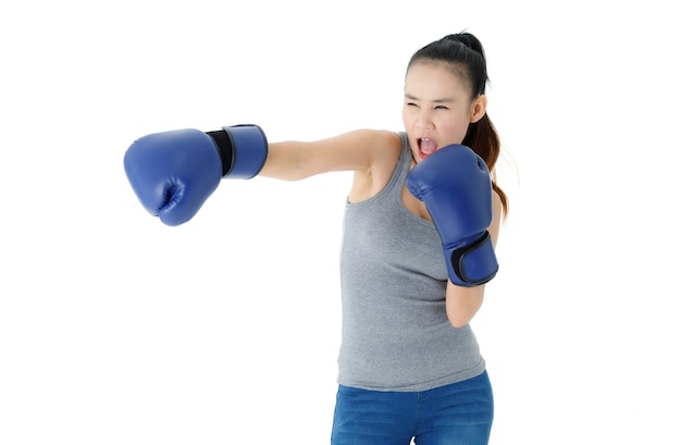 Jeune femme asiatique forte et déterminée dans des gants de boxe bleus frappant et frappant l'air sur fond blanc