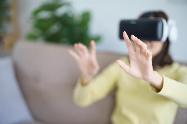 Jeune femme asiatique gamer portant la réalité virtuelle touchant l'air pendant l'expérience VR Futur joueur de technologie domestique passe-temps concept de plaisir ludique