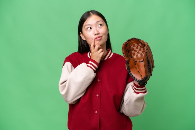 Jeune femme asiatique avec un gant de baseball sur fond isolé ayant des doutes en levant les yeux