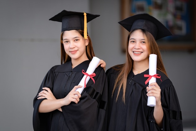 Une jeune femme asiatique heureuse diplômée de l'université en robe de graduation et en mortier détient un certificat d'études célébrant les résultats de l'éducation sur le campus universitaire. Éducation stock photo