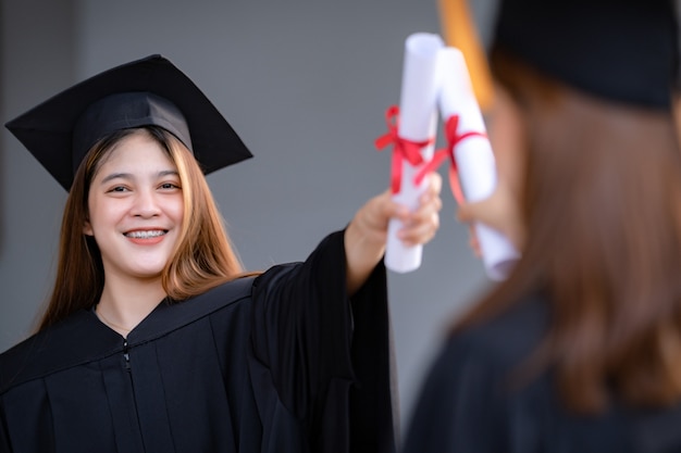 Une jeune femme asiatique heureuse diplômée de l'université en robe de graduation et en mortier détient un certificat d'études célébrant les résultats de l'éducation sur le campus universitaire. Éducation stock photo