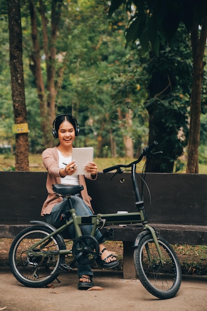 Une jeune femme asiatique heureuse en faisant du vélo dans un parc de la ville elle a souri en utilisant le vélo de transport concept respectueux de l'environnement