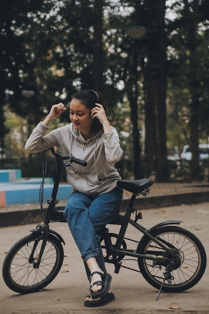 Photo une jeune femme asiatique heureuse marche et fait du vélo dans la rue du parc de la ville son sourire en utilisant le vélo de transport eco amical concept de style de vie des gens