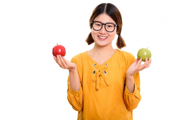 Jeune femme asiatique heureuse souriant tout en tenant la pomme rouge et la pomme verte