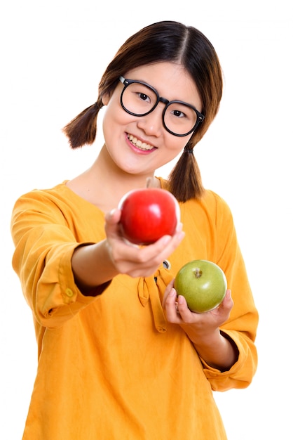 Jeune femme asiatique heureuse souriant tout en tenant la pomme verte et en donnant la pomme rouge