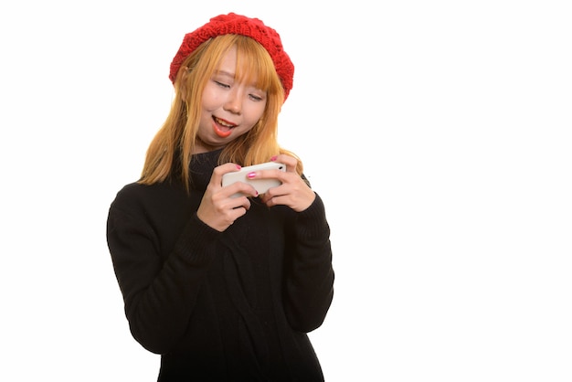 Jeune femme asiatique heureuse souriant et utilisant un téléphone mobile