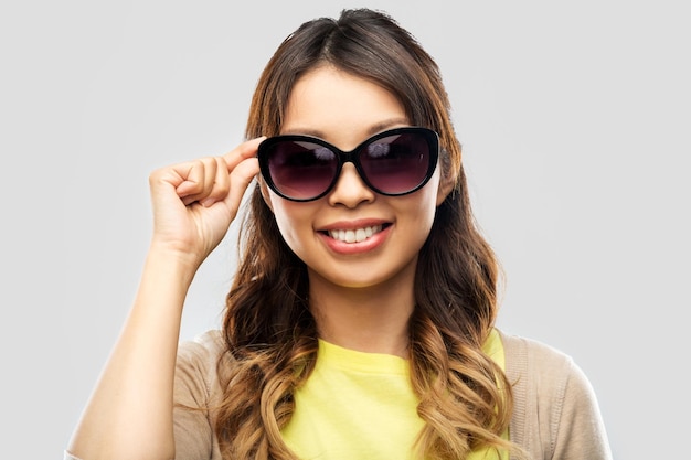 Une jeune femme asiatique heureuse et souriante avec des lunettes de soleil.
