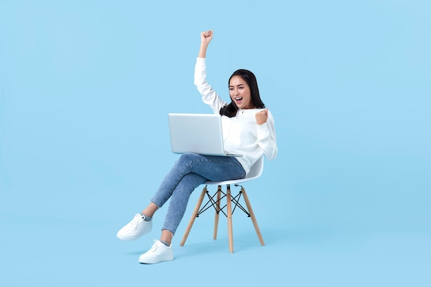 Jeune femme asiatique heureux souriant célébrer. Pendant qu'elle utilise un ordinateur portable