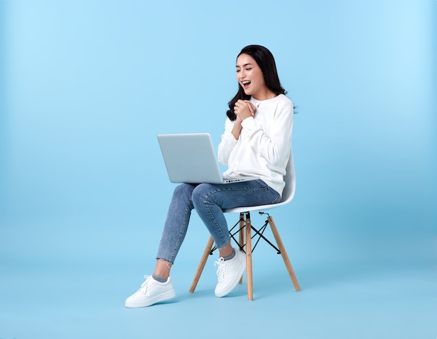 Jeune femme asiatique heureux souriant dans un cardigan blanc décontracté avec un espace bleu denim.