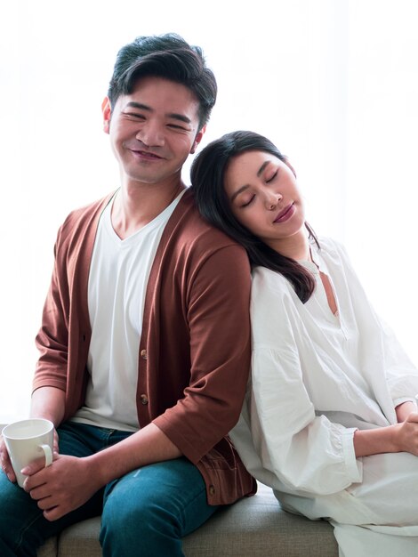 Jeune femme asiatique et homme à la maison avec une tasse de café dans les mains.