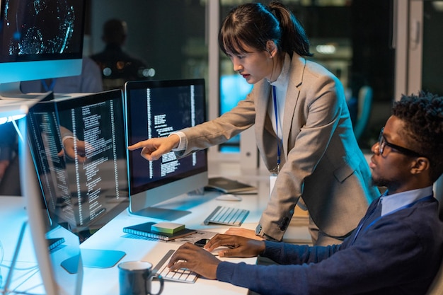 Jeune femme asiatique ingénieur informatique pointant sur des données sur écran d'ordinateur