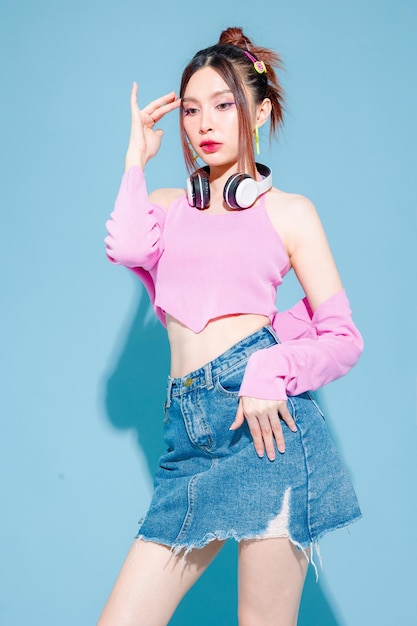 Jeune femme asiatique insouciante mignonne à la mode portant un casque et un patin à roulettes avec un corps mince parfait sur fond bleu isolé Modèle positif s'amusant et cool posant à l'intérieur du studio