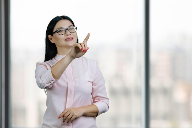 Une jeune femme asiatique interagit avec un écran virtuel invisible par son doigt