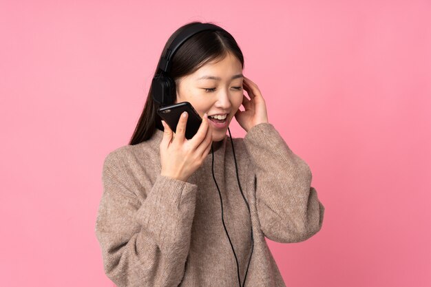 Jeune, femme asiatique, isolé, sur, mur rose, écouter musique, à, a, mobile, et, chant