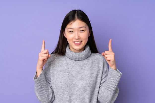Jeune femme asiatique sur isolé pointant vers le haut une excellente idée