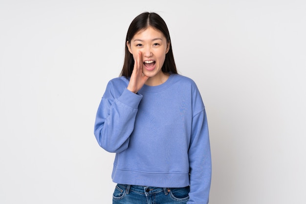 Jeune femme asiatique isolée sur le mur en criant avec la bouche grande ouverte