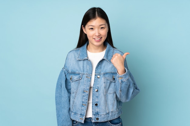 Jeune femme asiatique isolée en pointant vers le côté pour présenter un produit
